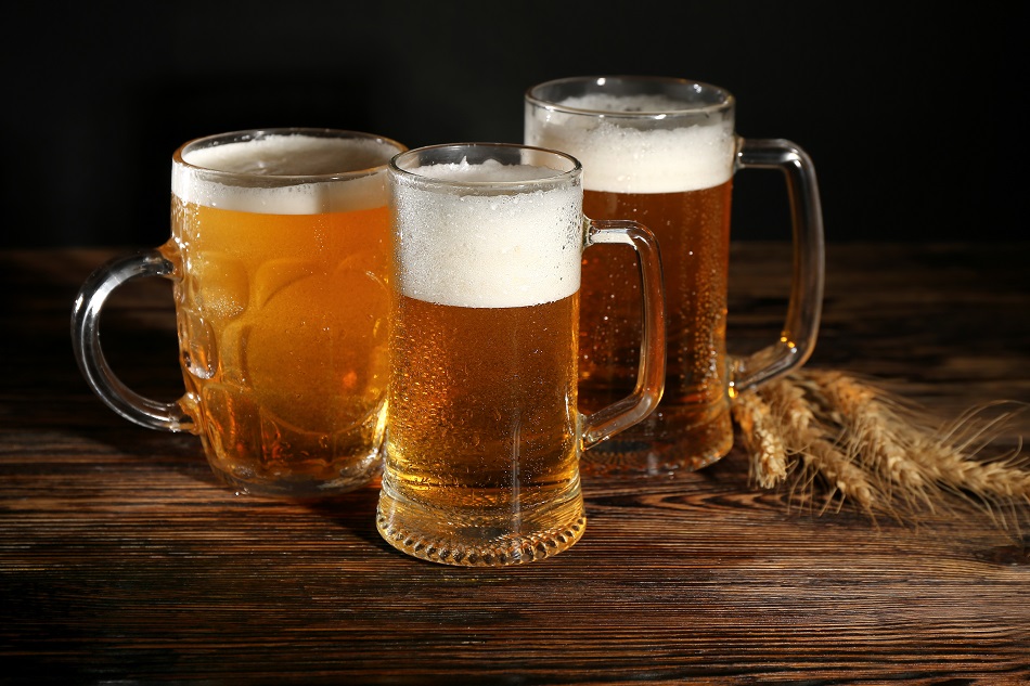 mugs of cold beer and spikelets on wooden table